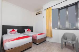 a hotel room with two beds and a window at Hotel O Transit 2 in Makassar