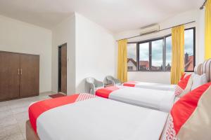 a hotel room with three beds and a window at Hotel O Transit 2 in Makassar