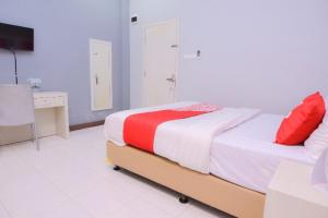 een slaapkamer met een bed met rode en witte lakens bij Capital O 2018 Ring Road Guest House Syariah in Banda Aceh