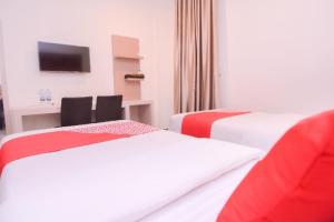 een hotelkamer met twee bedden en een bureau bij Capital O 2018 Ring Road Guest House Syariah in Banda Aceh