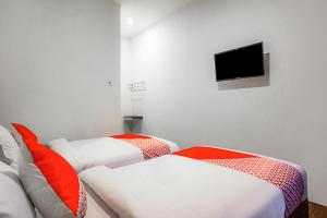 a room with two beds and a tv on the wall at Hotel O Citra Anggrek in Medan