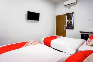 two beds in a room with a tv on the wall at Hotel O Citra Anggrek in Medan +27 photos
