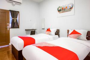 two beds in a room with red and white sheets at Hotel O Citra Anggrek in Medan