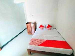 a small room with a bed with red pillows at Hotel O Griya Annisa in Tegal