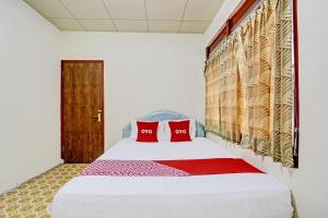 a bedroom with a white bed with red pillows at Hotel O Asta Guesthouse in Yogyakarta