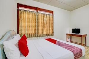 a bedroom with a bed with a red pillow and a window at Hotel O Asta Guesthouse in Yogyakarta +24 photos