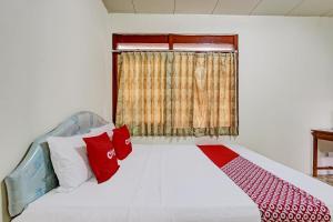 a bedroom with a bed with red and white pillows at Hotel O Asta Guesthouse in Yogyakarta