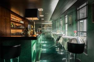 a restaurant with green walls and a bar with tables at Hotel Van Cleef in Bruges