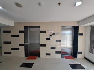 Dos ascensores en un vestíbulo con azulejos blancos y negros. en OYO Life 93106 Apartement Grand Sentraland By Andi, en Karawang
