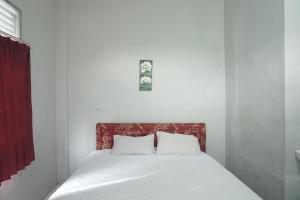 a bedroom with a white bed with a red headboard at Hotel O Azwa Gh Katingan Near Lapangan Sepak Bola Pegatan Hilir in Pagatan +52 photos