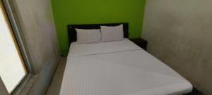 a bed in a small room with a green wall at Hotel O Azwa Gh Katingan Near Lapangan Sepak Bola Pegatan Hilir in Pagatan