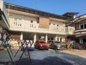 zwei Autos auf einem Parkplatz vor einem Gebäude geparkt in der Unterkunft OYO Life 93160 Kost Jenny Karawang in Karawang