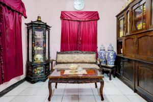 ein Wohnzimmer mit einem Sofa und roten Vorhängen in der Unterkunft OYO Life 90701 Kost Syariah Deris in Sumedang