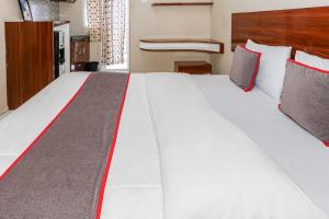 a large white bed with red and gray pillows at Capital O 93371 Pelangi Residence 5 in Tangerang