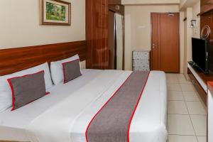 a bedroom with a large white bed with red and gray pillows at Capital O 93371 Pelangi Residence 5 in Tangerang