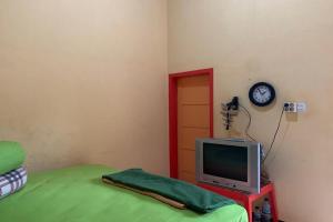 a room with a television and a clock on the wall at Hotel O Wisma Rima Melati in Tolo