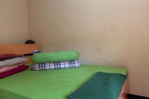 a room with a bed with green sheets and pillows at Hotel O Wisma Rima Melati in Tolo