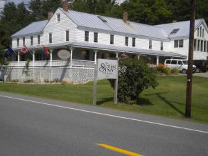 a white house with a dining dining sign in front of it at The Sterling Inn in Caratunk