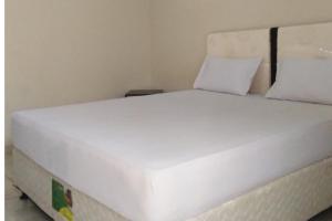 a white bed with two pillows on top of it at Hotel O Lembah Sriti Homestay Near Sirkuit Motor Cross Internasional 459 Lantan in Labuan Lombok +2 photos