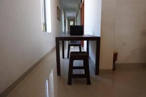 a wooden table with a stool and a laptop on it at OYO 94020 Lia Kost Syariah Near Perkuburan bontonompo kahar muzakkar in Rambia