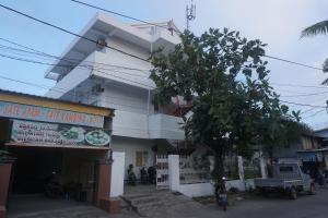 a white building with a tree in front of it at OYO 94020 Lia Kost Syariah Near Perkuburan bontonompo kahar muzakkar in Rambia