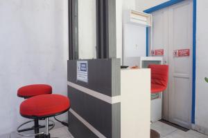 a waiting room with two red chairs and a counter at Hotel O Pondok Hitung Near GOR Kalegowa in Sungguminasa