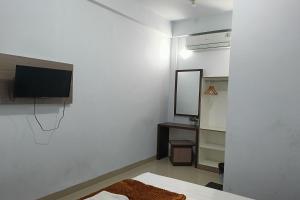 a bedroom with a bed and a tv and a mirror at Hotel O Kost Pak Dahlan Near Modern Estate in Sungguminasa +6 photos