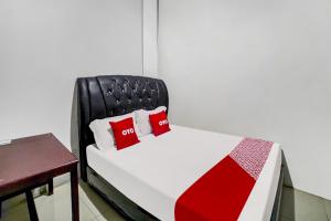 a bed with two red pillows on it next to a table at Hotel O near Citraland formerly Brayan Guest House in Medan