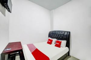 a small room with a bed with red pillows at Hotel O near Citraland formerly Brayan Guest House in Medan +26 photos