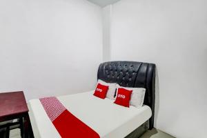 a bedroom with a bed with two red pillows at Hotel O near Citraland formerly Brayan Guest House in Medan