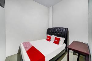 a bedroom with a bed and a chair with red pillows at Hotel O near Citraland formerly Brayan Guest House in Medan