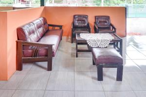 drie leren stoelen, een tafel en een bank bij Hotel O Griya Ketapang in Banyuwangi