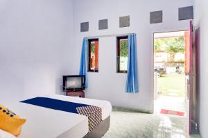 een slaapkamer met een bed, een tv en een raam bij Hotel O Griya Ketapang in Banyuwangi