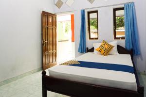 een slaapkamer met een bed met blauwe gordijnen bij Hotel O Griya Ketapang in Banyuwangi