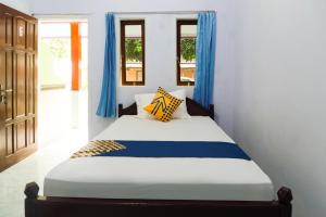 een bed in een kamer met blauwe gordijnen bij Hotel O Griya Ketapang in Banyuwangi