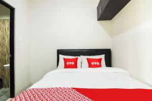 twee rode kussens op een bed met een rode deken bij OYO 3826 Columbus Residence K11 in Karawang