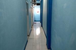 a hallway with blue walls and a tile floor at Hotel O Homestay 47 Latanete Near Living Plaza in Makassar