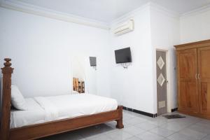 une chambre avec un lit et une télévision au mur dans l'établissement OYO Life 92886 Rumah Nyaman Radhika 2 Syariah, à Tuban