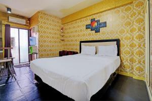 een slaapkamer met een groot wit bed met geel behang bij OYO Life 92978 Apartement Gateway Cicadas By Az Pro in Bandung