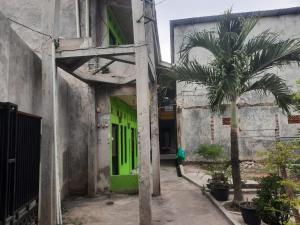a building with a green door and a palm tree at OYO Life 93023 Kost Bulan Karawang in Karawang