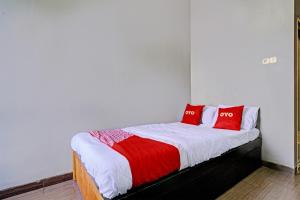 a bedroom with a bed with red pillows on it at OYO 93328 Graha Citra Syariah in Karajaan