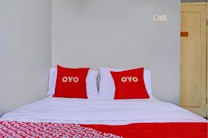 a bed with two red pillows on top of it at OYO 93328 Graha Citra Syariah in Karajaan +18 photos