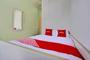 a bed with two red pillows in a room at OYO 93328 Graha Citra Syariah in Karajaan
