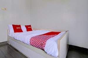 a bed with red and white pillows on it at OYO 93328 Graha Citra Syariah in Karajaan