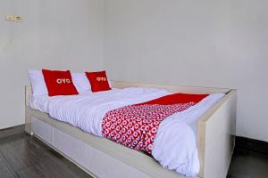 a bed with red and white pillows on it at OYO 93328 Graha Citra Syariah in Karajaan