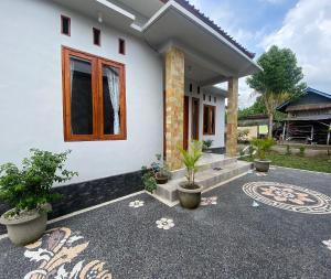 ein weißes Haus mit einem Fenster und Topfpflanzen in der Unterkunft Hotel O Gians Homestay Near SMKN 2 Kuripan in Lembuak