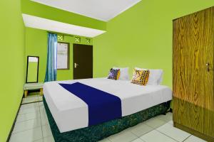 a bedroom with a large bed with green walls at OYO Life 91116 Pelangi Residence Syariah in Jatiroke +20 photos