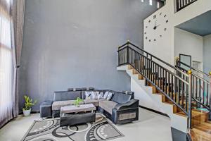 a living room with a couch and a staircase at OYO Life 91177 Desa Wisata Duren Sari in Tasikmadu