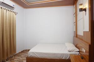 a small bedroom with a bed and a curtain at Hotel O Pondom Danu 77 in Kendari