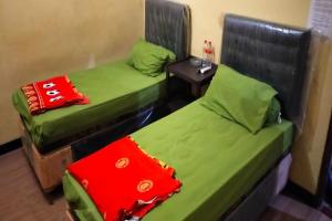 two twin beds in a room with a table at Hotel O Aida Lestari in Sebulu